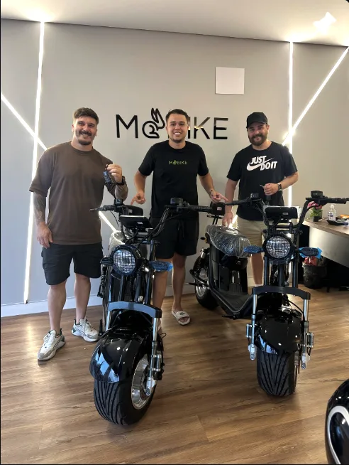 Equipe da Môbike Ingleses com duas scooters elétricas pretas na loja